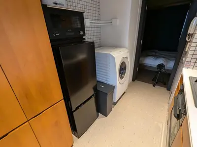 a small kitchen with a washing machine and a microwave at Family and Group stay, Private house close to Shinjuku in Tokyo