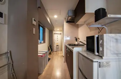 a small kitchen with white appliances and a wooden floor at Daily Urban Lodge \u65b0\u5bbf\u30bc\u30f37 in Tokyo