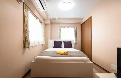 a bedroom with a bed with a yellow animal laying on it at Daily Urban Lodge \u65b0\u5bbf\u30bc\u30f37 in Tokyo