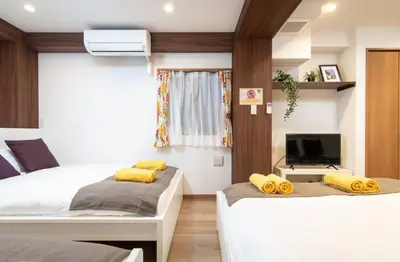two beds with yellow pillows in a room at Daily Urban Lodge \u65b0\u5bbf\u30bc\u30f37 in Tokyo