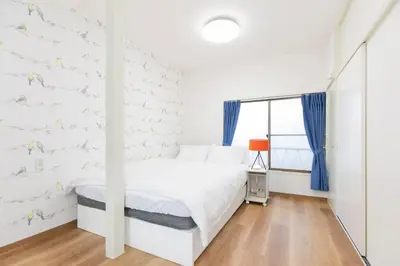 a white bedroom with a bed and a window at Forest Guest House Shinjuku city center in Tokyo