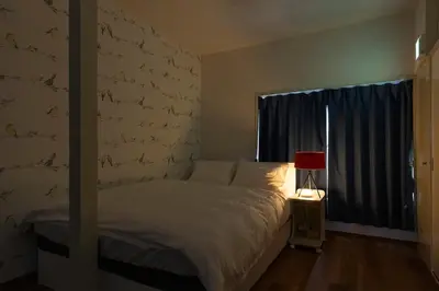 a bedroom with a bed with a red lamp and a window at Forest Guest House Shinjuku city center in Tokyo
