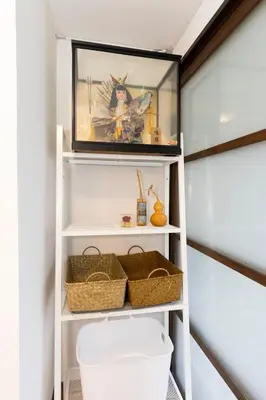 a shelf in a bathroom with baskets and a picture at Forest Guest House Shinjuku city center in Tokyo