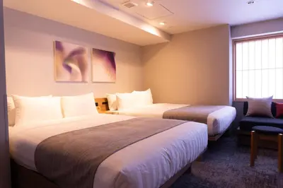 a hotel room with two beds and a chair at Premium Apart MONday GINZA EAST in Tokyo