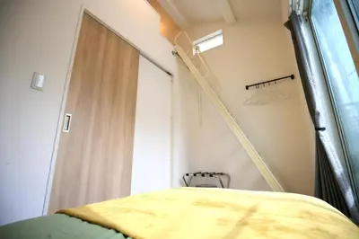 a room with a bed and a ladder next to a window at HAMA HILLS Shinjuku House in Tokyo