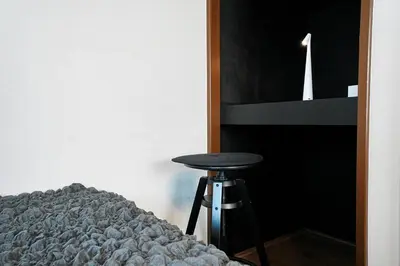 a stool sitting next to a bed next to a shelf at Zen Sleep Tokyo Ikegami in Tokyo