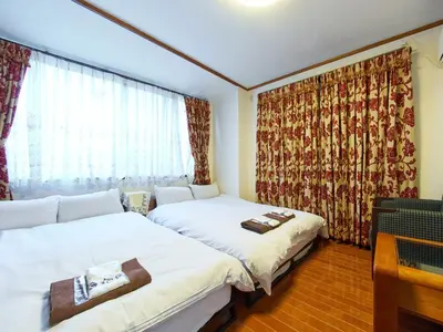 two beds in a small room with a window at Koka House TOKYO ASAKUSA in Tokyo