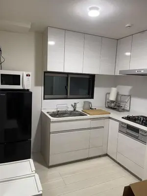 a kitchen with white cabinets and a black refrigerator at Mark\u7684\u8db3\u7acb\u6c11\u5bbf in Tokyo