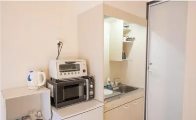 a small kitchen with a microwave and a sink at iine house hatagaya in Tokyo