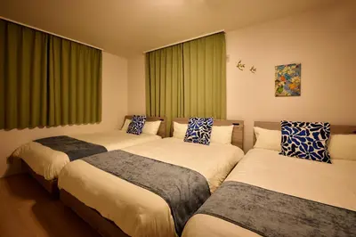 three beds in a room with green curtains at Simple Stay ShibuyaShinjyuku in Tokyo