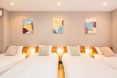 three beds in a room with paintings on the wall at Mori hotel Akihabara 1 in Tokyo