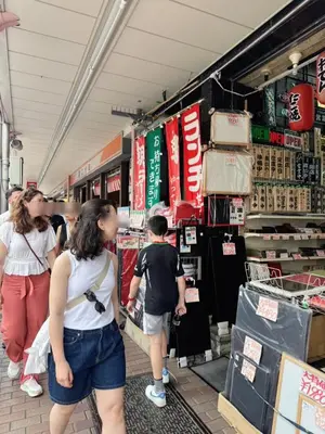 a group of people walking through a store aisle at househotel\u4e0a\u91ce \u5165\u8c37 in Tokyo