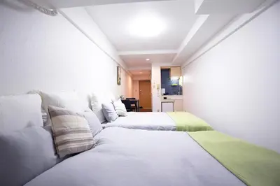 two beds in a room with white walls at \u6b4c\u821e\u4f0e\u753a\u306e\u96a0\u308c\u5bb6 \u65b0\u5bbf\u30a8\u30ea\u30a2\u89b3\u5149\u306b\u4fbf\u5229Qo4 in Tokyo