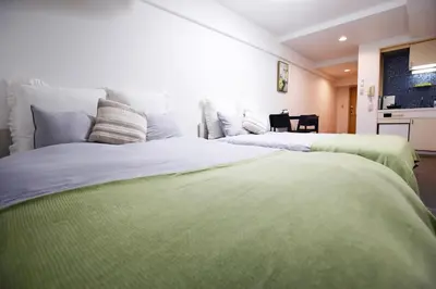 a bedroom with two beds with green sheets at \u6b4c\u821e\u4f0e\u753a\u306e\u96a0\u308c\u5bb6 \u65b0\u5bbf\u30a8\u30ea\u30a2\u89b3\u5149\u306b\u4fbf\u5229Qo4 in Tokyo