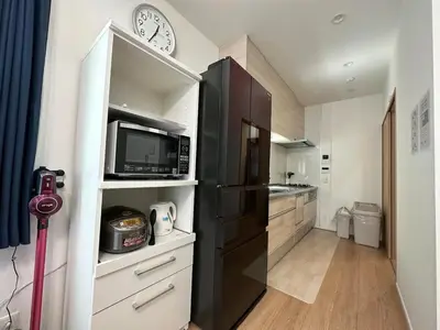 a kitchen with a black refrigerator and a clock at Fit-Inn Komagome JR Line and Komagome 2 min walk Direct access to Shinjuku Ikebukuro Shibuya Akihabara Ueno in Tokyo