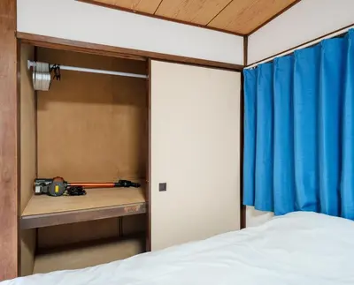 a bedroom with a bed and a blue curtain at Sakura House Meguro in Tokyo