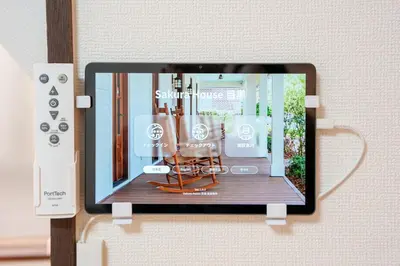 a tablet hanging on a wall with a wii controller at Sakura House Meguro in Tokyo