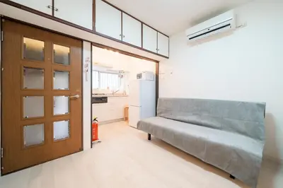a room with a couch and a door and a refrigerator at Sakura House Meguro in Tokyo