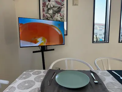 a dining room with a table and a tv on the wall at Mark\u7684\u8db3\u7acb\u6c5f\u5317\u7ad9\u6c11\u5bbf in Tokyo
