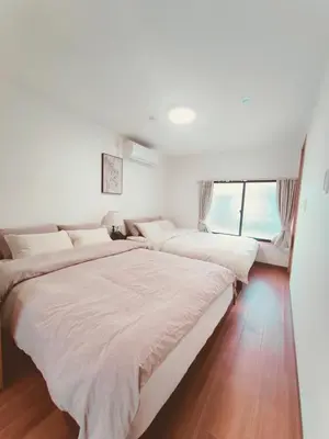 two beds in a room with white walls and wood floors at Moon Hotel in Tokyo