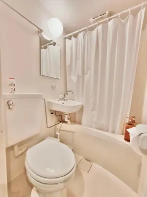 a white bathroom with a toilet and a sink at Moon Hotel in Tokyo