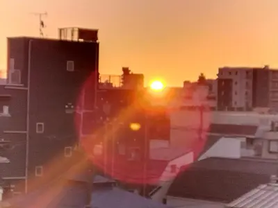a sunset in a city with buildings and the sun at Sun and Moon\u30db\u30c6\u30eb302 in Tokyo
