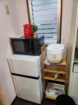 a microwave sitting on top of a refrigerator at \u5409\u5c4b-\u65b0\u5bbf in Tokyo