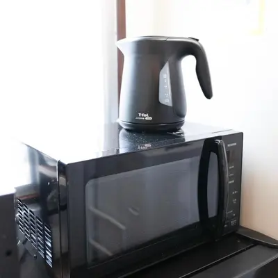 a coffee pot sitting on top of a microwave at \u5409\u5c4b-\u65b0\u5bbf in Tokyo