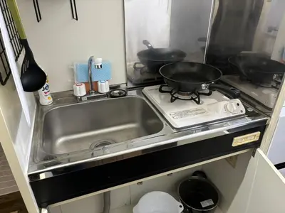 a kitchen with a sink and a stove with pots and pans at \u5409\u5c4b-\u65b0\u5bbf in Tokyo