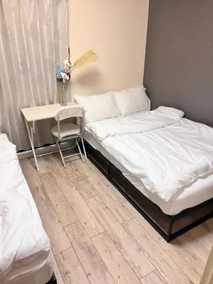 two beds in a room with a table and a chair at Toyo Shinagawa in Tokyo