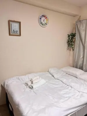 a bed with white sheets and a clock on the wall at Toyo Shinagawa in Tokyo