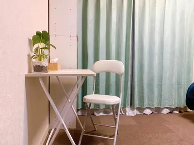 a white chair sitting next to a table with a green curtain at Toyo Shinagawa in Tokyo