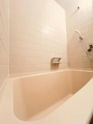a white bath tub in a white tiled bathroom at Toyo Shinagawa in Tokyo