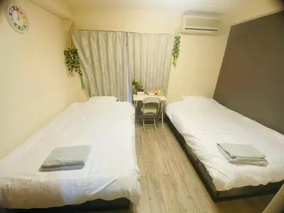 two beds in a room with a table and a chair at Toyo Shinagawa in Tokyo