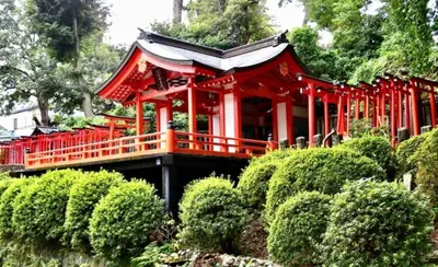 a red temple in a garden with bushes at MY House YANESEN Tokyo2 in Tokyo