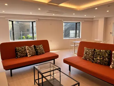 a waiting room with two orange couches and a table at MY House YANESEN Tokyo2 in Tokyo