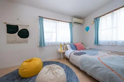 a bedroom with two beds and a table and windows at HOTEL Flag Tokyo in Tokyo