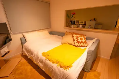 a bedroom with a bed with a yellow blanket on it at HOTEL Flag Tokyo in Tokyo