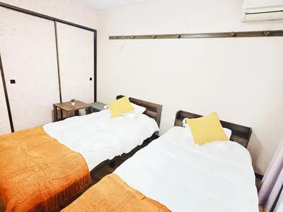 two beds in a room with white and yellow pillows at Liberty Corp 102 - Vacation STAY 18545 in Tokyo