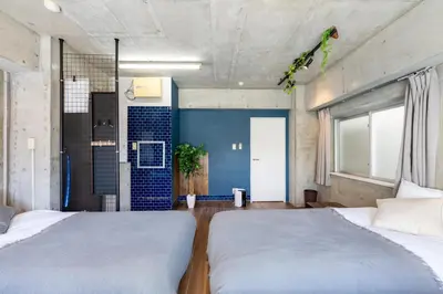 a bedroom with two beds and a blue wall at Stayloop\u5e73\u4e95 in Tokyo