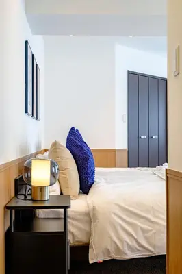 a bedroom with a bed with blue pillows and a table at Penthouse Apartment with Skytree View - 94sqm Luxury Suite - Miilo ASAKUSA EAST in Tokyo