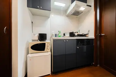 a small kitchen with a stove and a microwave at Shinjuku ,2 minutes from the station in Tokyo
