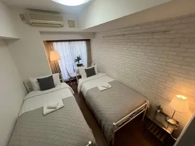 two beds in a room with a brick wall at Shinjuku ,2 minutes from the station in Tokyo