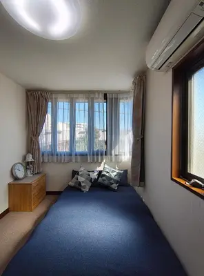 a bedroom with a large blue bed with windows at live in Onsen in Tokyo