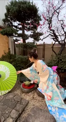 a woman in a kimono holding a green umbrella at \u65b0\u5bbf \u65b0\u5927\u4e45\u4fdd\u99c5108 \u5e73\u7c73\u65e5\u672c\u5ead\u5712\u306e\u5bbf in Tokyo