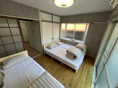two beds in a small room with a window at Doragon House in Tokyo