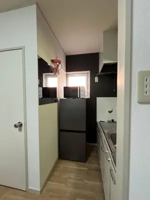 a small kitchen with a refrigerator and a sink at Doragon House in Tokyo