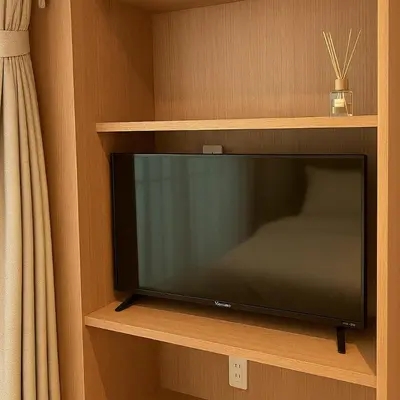 a flat screen tv sitting on a wooden shelf at \u9752\u9ea6\u5bbf\u6cca \u65e9\u7a3b\u7530\u5e97 in Tokyo