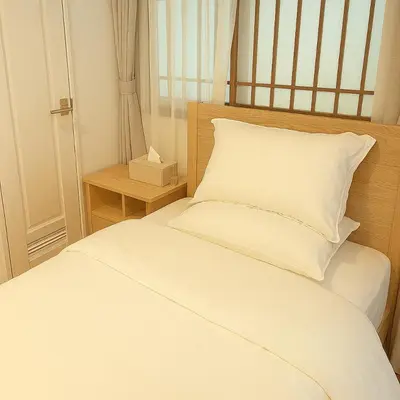 a white bed with a white pillow and a nightstand at \u9752\u9ea6\u5bbf\u6cca \u65e9\u7a3b\u7530\u5e97 in Tokyo