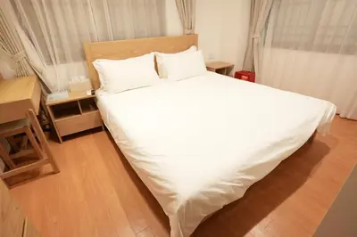 a bedroom with a white bed with a wooden floor at \u9752\u9ea6\u5bbf\u6cca \u65e9\u7a3b\u7530\u5e97 in Tokyo